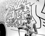 Keith Haring, a pioneer of queer art, poses with his iconic figures in this black and white image.