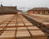 Posa di armature su tavelloni in laterizio, con sullo sfondo facciate in pietra e mattoni di edifici storici.