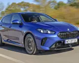 Niebieskie BMW serii 1 (f21) w ruchu, z kierowcą za kierownicą.