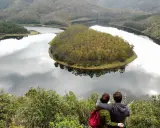 Pareja abraza contemplando el meandro del río en Las Hurdes, un paisaje de colinas verdes y agua serena.