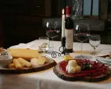 Tagliere con formaggi e bresaola, accompagnati da vino rosso e candela. Un assaggio dei piatti tipici Valtellina.