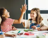 Kinder geben sich High-Five bei einer Gruppenarbeit. Sie lernen und arbeiten zusammen, was tolle Gruppenarbeit Methoden zeigt.