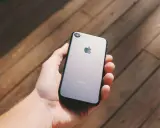 Dłoń trzyma szarego iPhone'a. Chcesz wiedzieć, jak sprawdzić, czy iPhone jest oryginalny? Zwróć uwagę na detale.