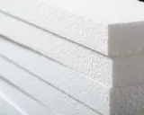 Stapel weißer Styroporplatten, bereit für die Isolierung. Die feine, körnige Textur des Materials ist gut sichtbar.