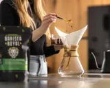 Frau bereitet Kaffee zu, um zu zeigen, was ist Caffe Latte. Kaffeepulver rieselt aus Löffel in Filter.