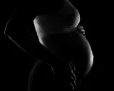 Silhuett av en gravid kvinna som håller sin mage. Bilden kan associeras med vena cava syndrom gravid.
