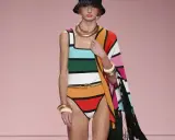 Modella con costume a righe colorate e cappello nero. Un'abbronzatura a strisce perfetta per l'estate, completata da gioielli dorati e un coprispalle a fantasia.