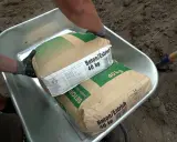Zwei Säcke Beton/Estrich 40 kg liegen in einer Schubkarre. Verschiedene Estrich Arten sind für Bauprojekte wichtig.