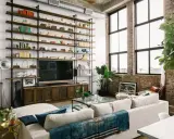 Soggiorno con scaffalatura a tutta parete, TV e divano bianco. Il soffitto alto 5 metri crea un'atmosfera ariosa, accentuata dalle grandi finestre.