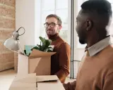 Dos hombres desempaquetan cajas en un nuevo hogar, listos para su movilidad geográfica y la nueva etapa de renta.