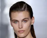 Ein Model mit glänzenden, nassen Haaren im Wet-Look-Stil, das einen intensiven Blick in die Kamera wirft.