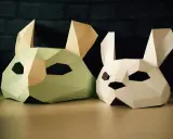 Två påskpyssel i papper: en ljusgrön och en vit kaninmask med stora öron.