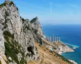 Widok na Skałę Gibraltarską z jaskinią, budynkami i morzem.