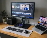 Stacja do edycji wideo z monitorem BenQ, laptopem, klawiaturą i kontrolerem. Na ekranie widać oś czasu i wykresy, co sugeruje pracę nad parametrami monitora.