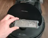 Hand hält einen stark verschmutzten Staubfilter eines Roborock Saugroboters, bereit für die Reinigung.