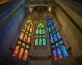 Ventanas de vidrieras de colores vibrantes, que narran la historia del vidrio, iluminan el interior de una catedral con tonos cálidos y fríos.