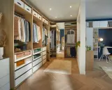 Un dressing aménagé pour un dressing à faire soi même, avec des étagères en bois, des tiroirs et des vêtements bien rangés.