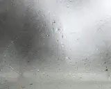 Gotas de agua sobre un cristal, reflejando un cielo nublado. La **temperatura de rocío** se siente en el aire húmedo.