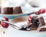 Coulant de chocolate con interior fundido, espolvoreado con azúcar glas y acompañado de cerezas frescas.