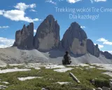 Osoba siedzi na tle majestatycznych Tre Cime, podziwiając widok. Idealne miejsce na trekking!