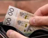 Dłoń wkłada do portfela banknoty 100 zł. Czy to na bieżące wydatki, czy może na 13. emeryturę?