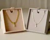 Due collane, una in oro e una in argento, con pendente scintillante, presentate in eleganti scatole.