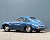 Blauer Porsche 1600 Super Coupé, ein Klassiker mit hohem Wert, steht vor einer grauen Wand.
