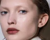 Primer plano de un rostro cuadrado con ojos azules y labios oscuros.
