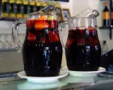 Dwa dzbanki z ciemnym napojem i owocami, idealne na lato. Przepis na tinto de verano.