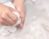 Ręce piorą biały obrus, próbując usunąć stare plamy.