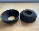 Zwei schwarze EPP-Platten, geformt wie Trichter und Zylinder, liegen auf einer Holzoberfläche.
