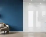 Un fauteuil confortable près d'un mur bleu profond, contrastant avec une cuisine blanche aux finitions peinture mat ou satin.