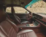 Das **Porsche 944 Interieur** mit braunen Ledersitzen und Armaturenbrett. Ein Blick auf das Lenkrad, den Schalthebel und das Radio.
