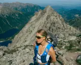 Kobieta w okularach i niebieskim plecaku na tle górskich krajobrazów. Beskid Śląski oferuje takie widoki i atrakcje.