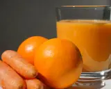 Pomarańcze i marchewki obok szklanki soku. Idealne składniki na zdrową dieta warzywno owocowa.