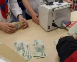 Ręce liczą banknoty 100 i 200 zł. Obok maszyna do liczenia pieniędzy. W tle gazety. Płatność gotówką do jakiej kwoty jest dozwolona?