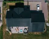Villa med solceller och ett modernt batterilager. Uteplats med spabad och utemöbler. En vit bil parkerad på uppfarten.