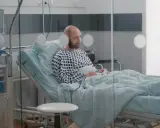 Mężczyzna w szpitalnym łóżku, z tlenem w nosie, czeka na wypis. Jego pobyt w szpitalu a zwolnienie lekarskie to teraz kluczowe kwestie.