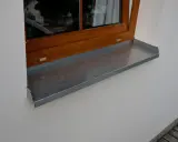 Szary parapet zewnętrzny plastikowy pod drewnianym oknem.