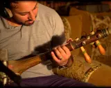 Un homme joue d'un instrument à corde marocain, un guembri, devant un microphone.