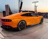 Ein leuchtend oranger AMG GT XX steht auf einer Bühne, beleuchtet vom Abendhimmel.