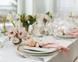 En vacker fest dukning med rosa blommor, glas och menyer.