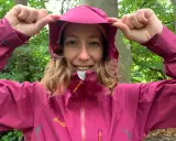 Kvinna i skogen drar upp huvan på sin rosa jacka, redo för 5000 vattenpelare.