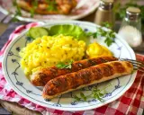 Zwei gegrillte Bratwürste mit Kartoffelsalat und Senf. Ein leckeres Rezept für Bratwurst selber machen.