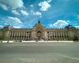 Grand Palais w Paryżu, jeden z najważniejszych zabytków Paryża, z kolumnadą i kopułą pod błękitnym niebem.