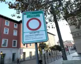 Señal de etiqueta medioambiental en Zaragoza, indicando zona de bajas emisiones con excepciones para carga, descarga, taxis, bicicletas y residentes.
