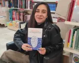 Una giovane donna sorride in libreria, tenendo in mano il libro "Dove si nascondono le lacrime".