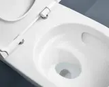 Vue rapprochée d'une cuvette de WC blanche, siège relevé, suggérant le sens d'ouverture de la porte des toilettes.
