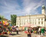 Kolorowy jarmark na rynku na Kazimierzu w Krakowie. Balony, stragany z pamiątkami i ludzie spacerujący pod jasnym niebem.
