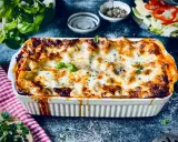 Herzhafte vegetarische Lasagne mit geschmolzenem Käse und frischem Basilikum, serviert in einer weißen Auflaufform.